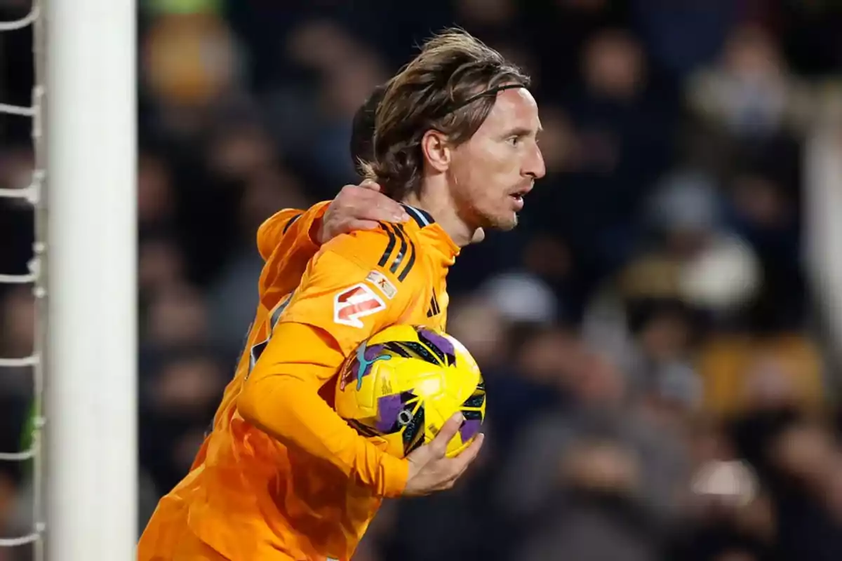 Soccer player in orange uniform holding a ball during a match. Soccer player in orange uniform holding a ball during a match.