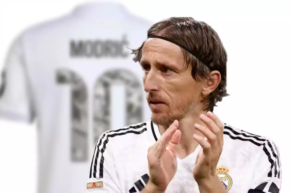 Real Madrid player applauding with a blurred white jersey in the background showing the number 10 and the name Modric