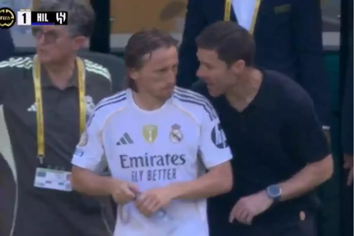 Un jugador del Real Madrid escucha atentamente las indicaciones de un entrenador durante un partido de fútbol.