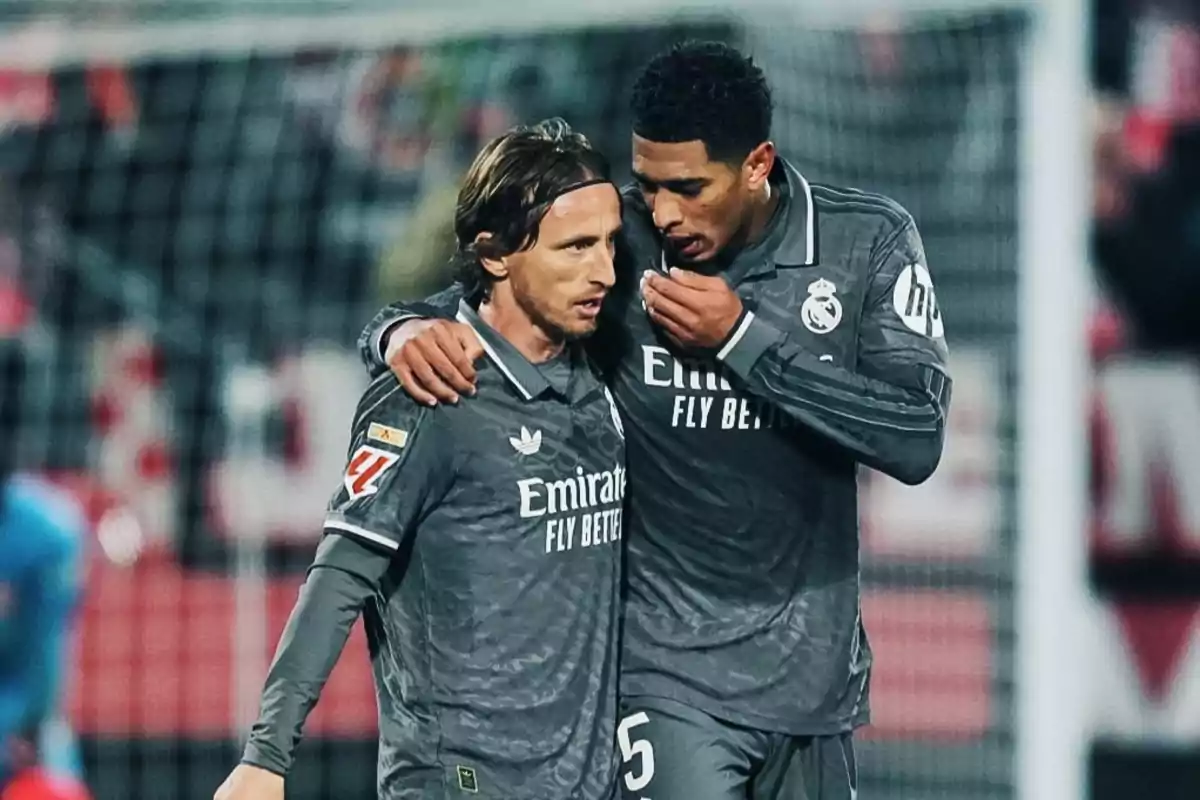 Two Real Madrid soccer players chat on the field during a match.