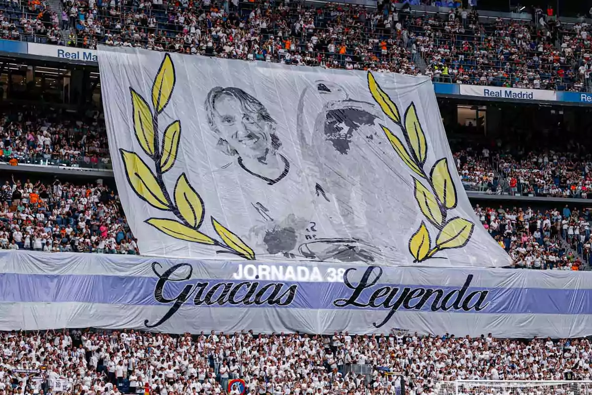 Un gran cartel en un estadio de fútbol muestra un retrato de un jugador con hojas de laurel y el mensaje Un gran cartel en un estadio de fútbol muestra un retrato de un jugador con hojas de laurel y el mensaje