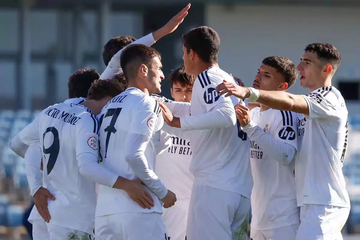 Un grupo de jugadores de fútbol con uniformes blancos celebrando en el campo.