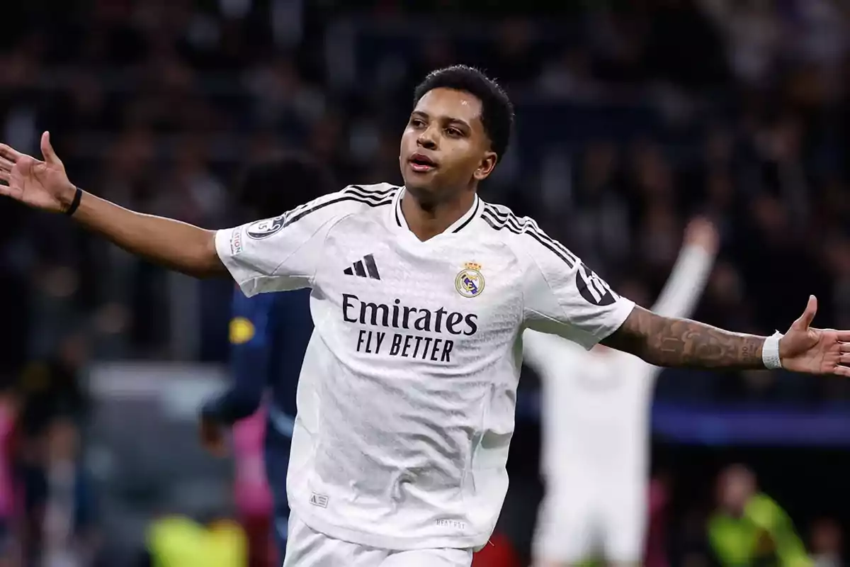 A soccer player in a white Real Madrid uniform celebrates with his arms outstretched in a stadium. A soccer player in a white Real Madrid uniform celebrates with his arms outstretched in a stadium.