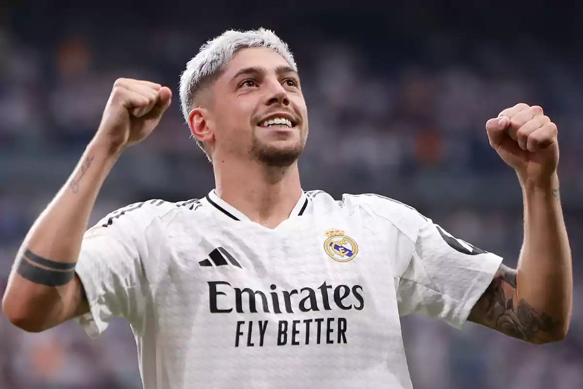 A soccer player in a white uniform celebrates with his arms raised in a stadium. A soccer player in a white uniform celebrates with his arms raised in a stadium.