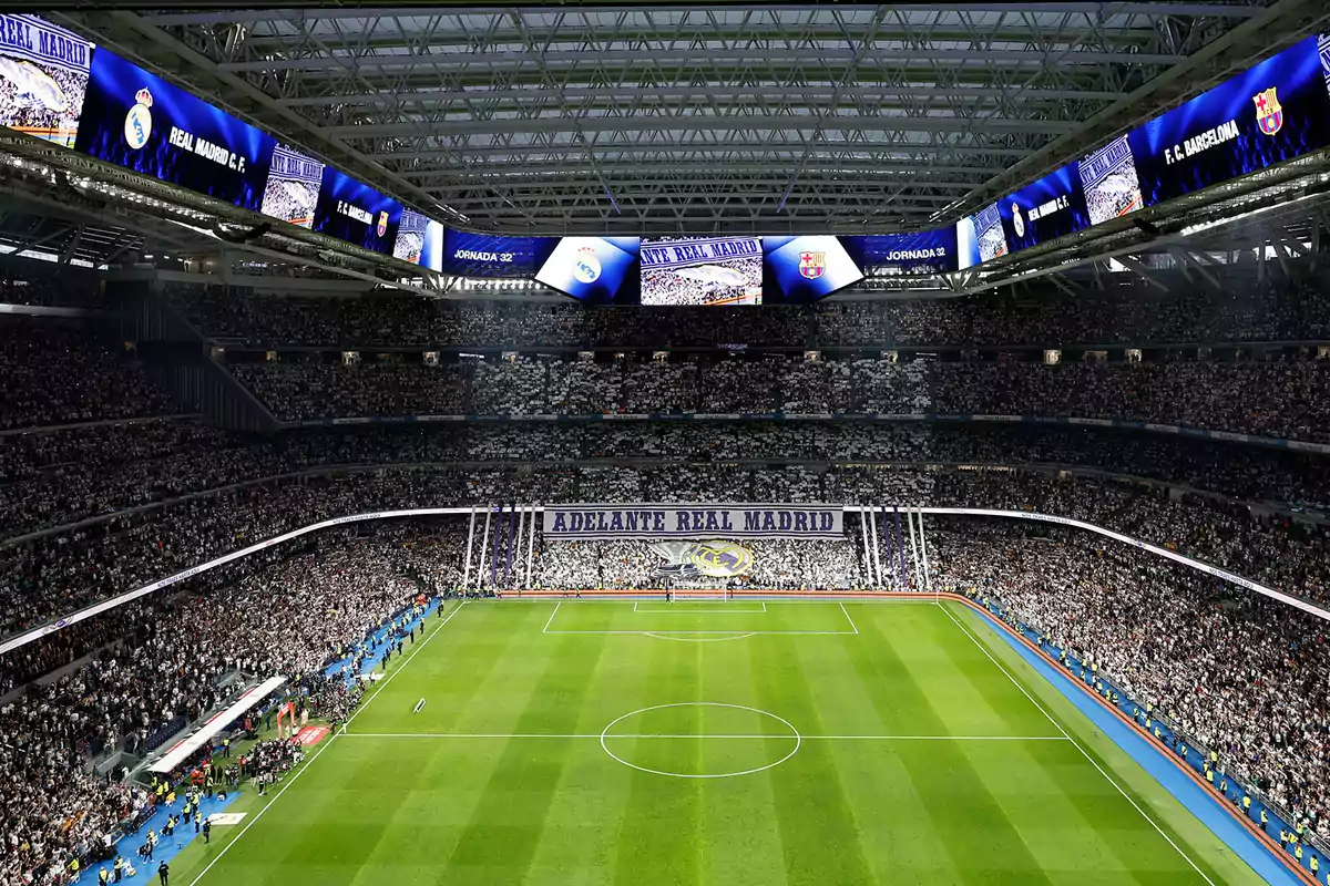 A soccer stadium full of spectators with a large banner that says "Go Real Madrid" and screens showing match information.