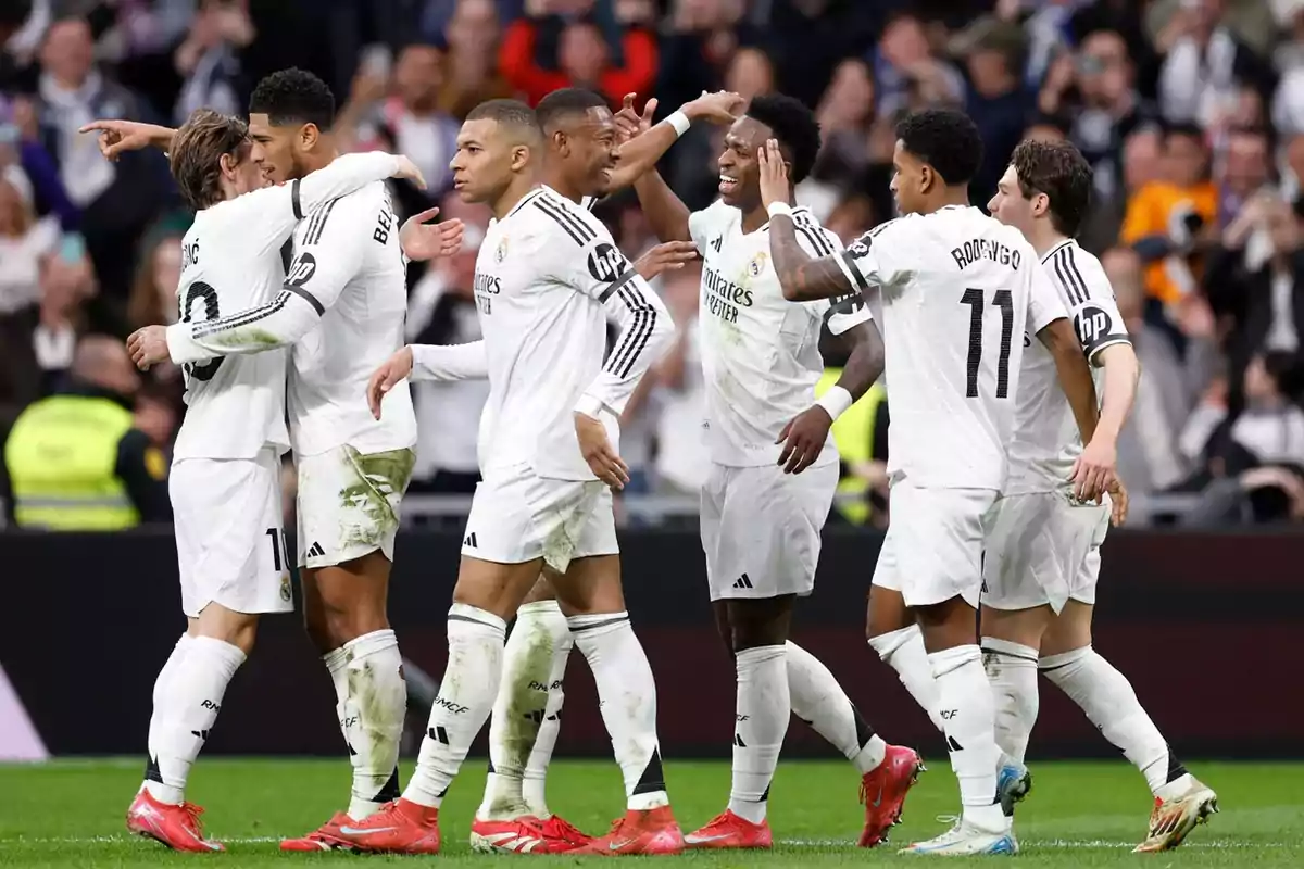 A group of players in white uniforms celebrating on the field during a match.