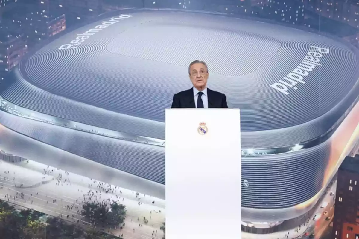 A man standing on a podium in front of a picture of the Real Madrid stadium.