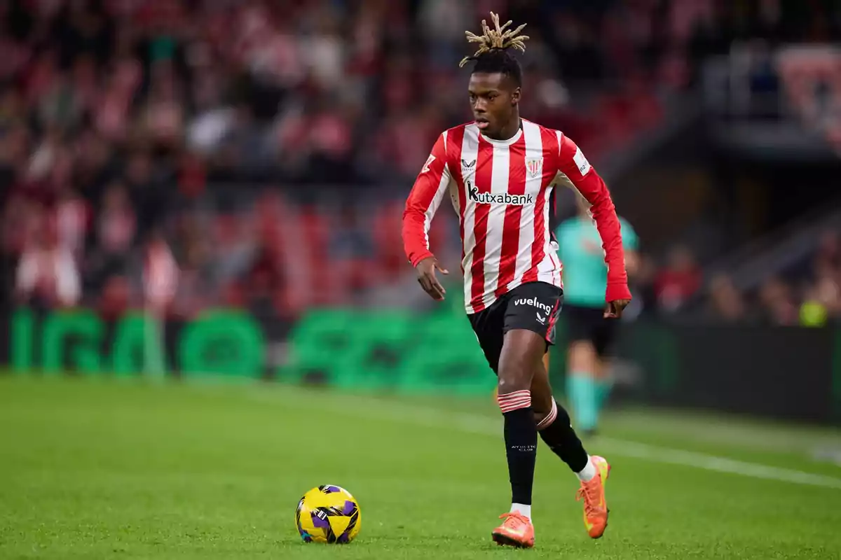 Athletic Club player in a red and white uniform running toward a ball in a stadium during a match Athletic Club player in a red and white uniform running toward a ball in a stadium during a match