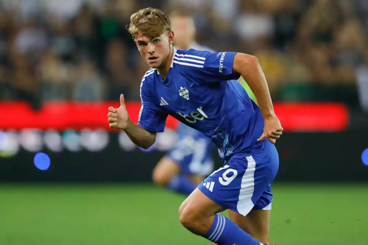 Soccer player in action wearing a blue uniform during a match. Soccer player in action wearing a blue uniform during a match.