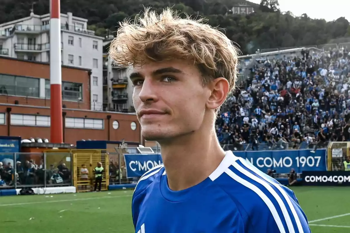 Young player wearing a blue jersey in a stadium with a crowd and buildings in the background Young player wearing a blue jersey in a stadium with a crowd and buildings in the background