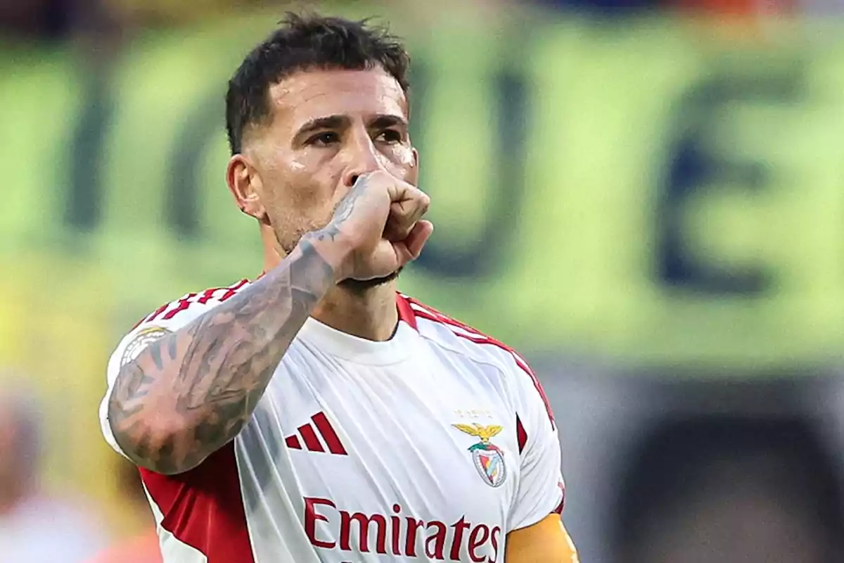 Futbolista con uniforme blanco y rojo del Benfica celebrando un gol llevándose el puño a la boca en un estadio Futbolista con uniforme blanco y rojo del Benfica celebrando un gol llevándose el puño a la boca en un estadio