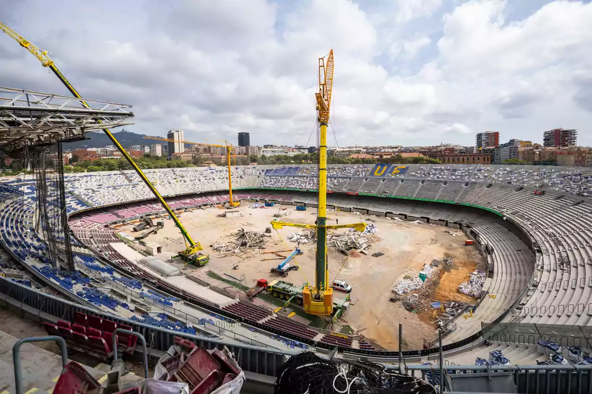 Estadio en proceso de remodelación con grúas y escombros en el campo central.