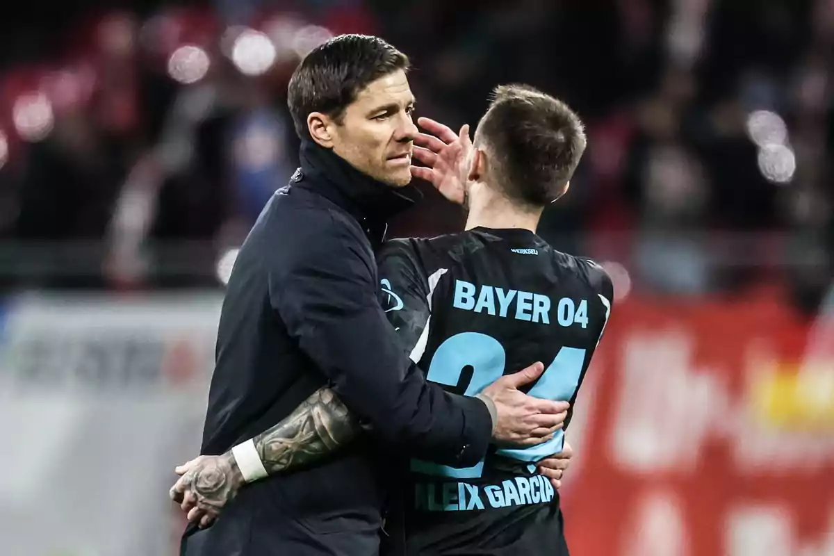 Entrenador abrazando a un jugador del Bayer 04 en el campo de fútbol durante un partido Entrenador abrazando a un jugador del Bayer 04 en el campo de fútbol durante un partido