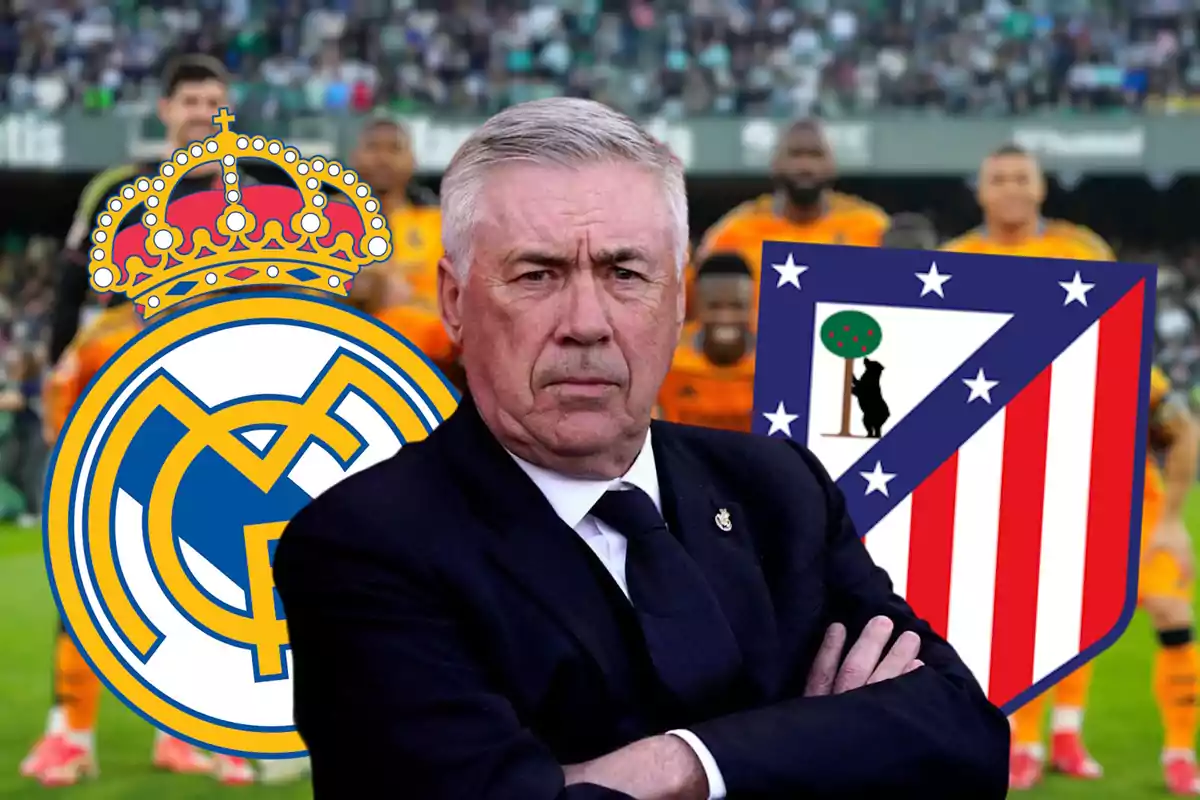 A man in a suit with crossed arms in front of the Real Madrid and Atlético de Madrid crests, with blurred players in the background.