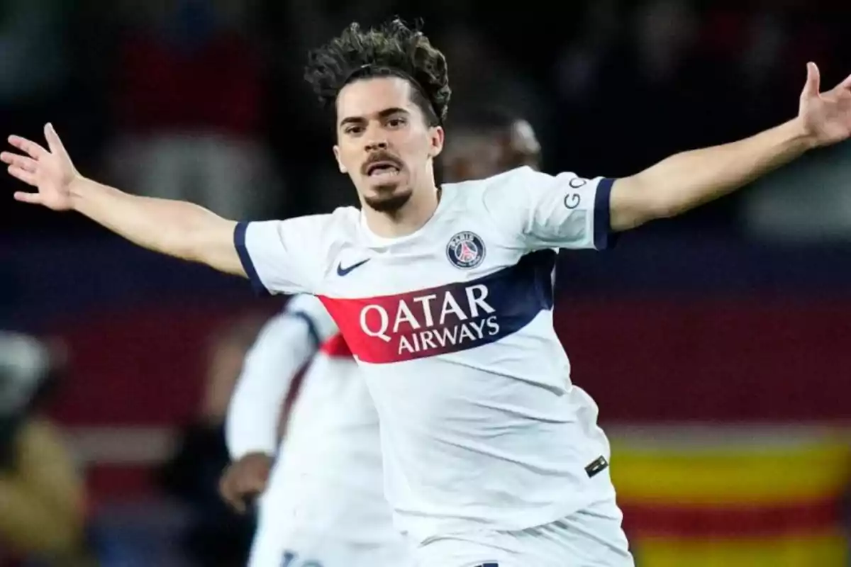 Jugador de fútbol celebrando un gol con los brazos extendidos mientras viste el uniforme del PSG.