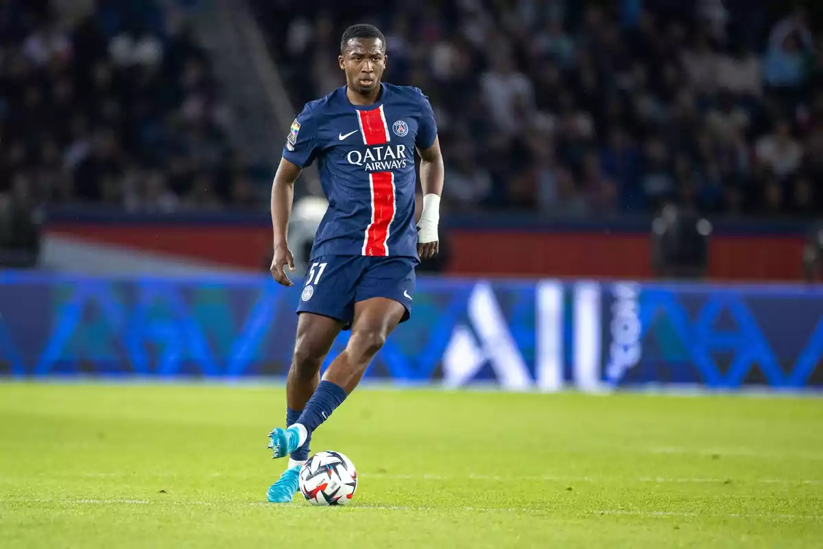 Futbolista del PSG con uniforme azul y franja roja controla el balón en el campo durante un partido Futbolista del PSG con uniforme azul y franja roja controla el balón en el campo durante un partido