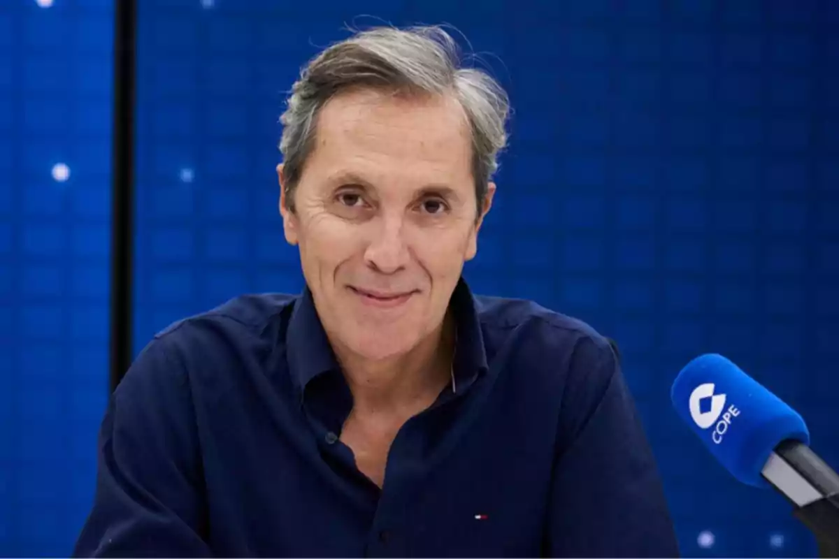 Gray-haired man in a blue jersey in front of a blue microphone with the COPE logo on a blue background.