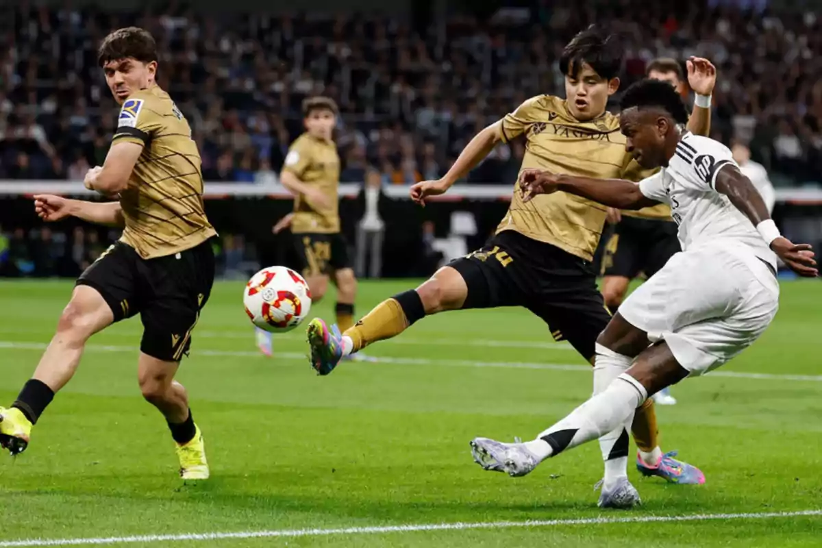 A player in a white uniform tries to control the ball while being challenged by two players in gold uniforms on a soccer field. A player in a white uniform tries to control the ball while being challenged by two players in gold uniforms on a soccer field.