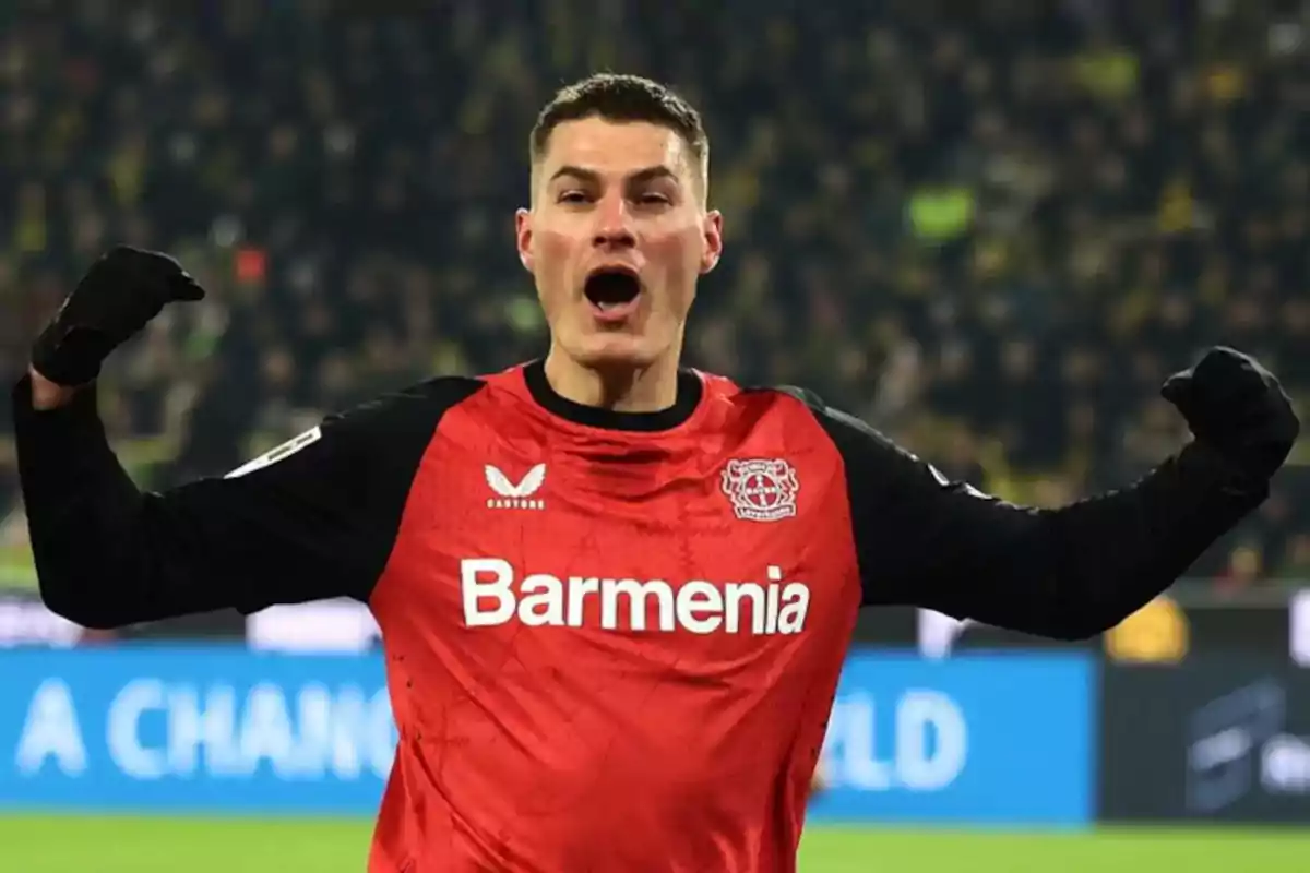 Futbolista del Bayer Leverkusen celebrando un gol con los brazos levantados en un estadio lleno de aficionados