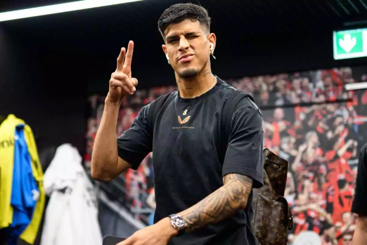 Joven con camiseta negra y mochila haciendo el signo de paz con los dedos y guiñando un ojo en un vestidor deportivo Joven con camiseta negra y mochila haciendo el signo de paz con los dedos y guiñando un ojo en un vestidor deportivo