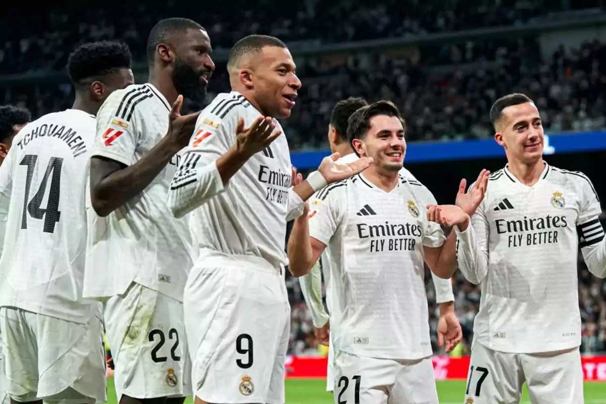 Real Madrid soccer players celebrate on the field with expressions of joy and camaraderie, wearing the team's white uniform. Real Madrid soccer players celebrate on the field with expressions of joy and camaraderie, wearing the team's white uniform.