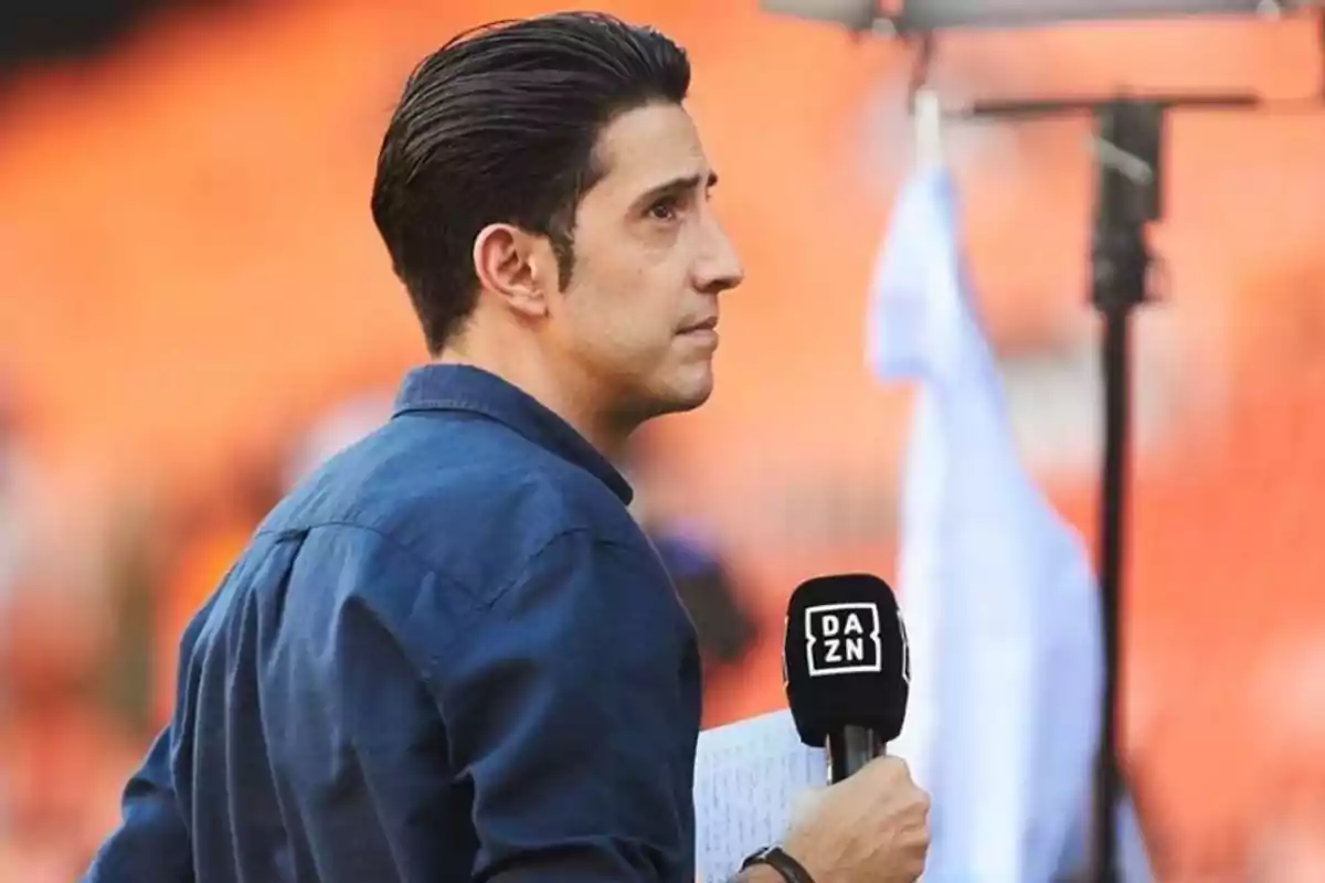 A man holding a DAZN microphone in a stadium.