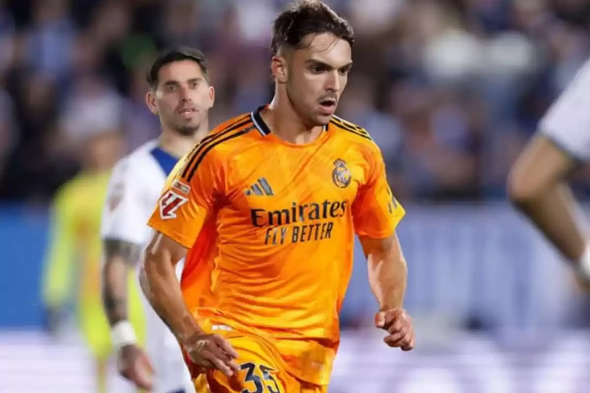 Un jugador de fútbol con uniforme naranja del Real Madrid corre en el campo durante un partido. Un jugador de fútbol con uniforme naranja del Real Madrid corre en el campo durante un partido.