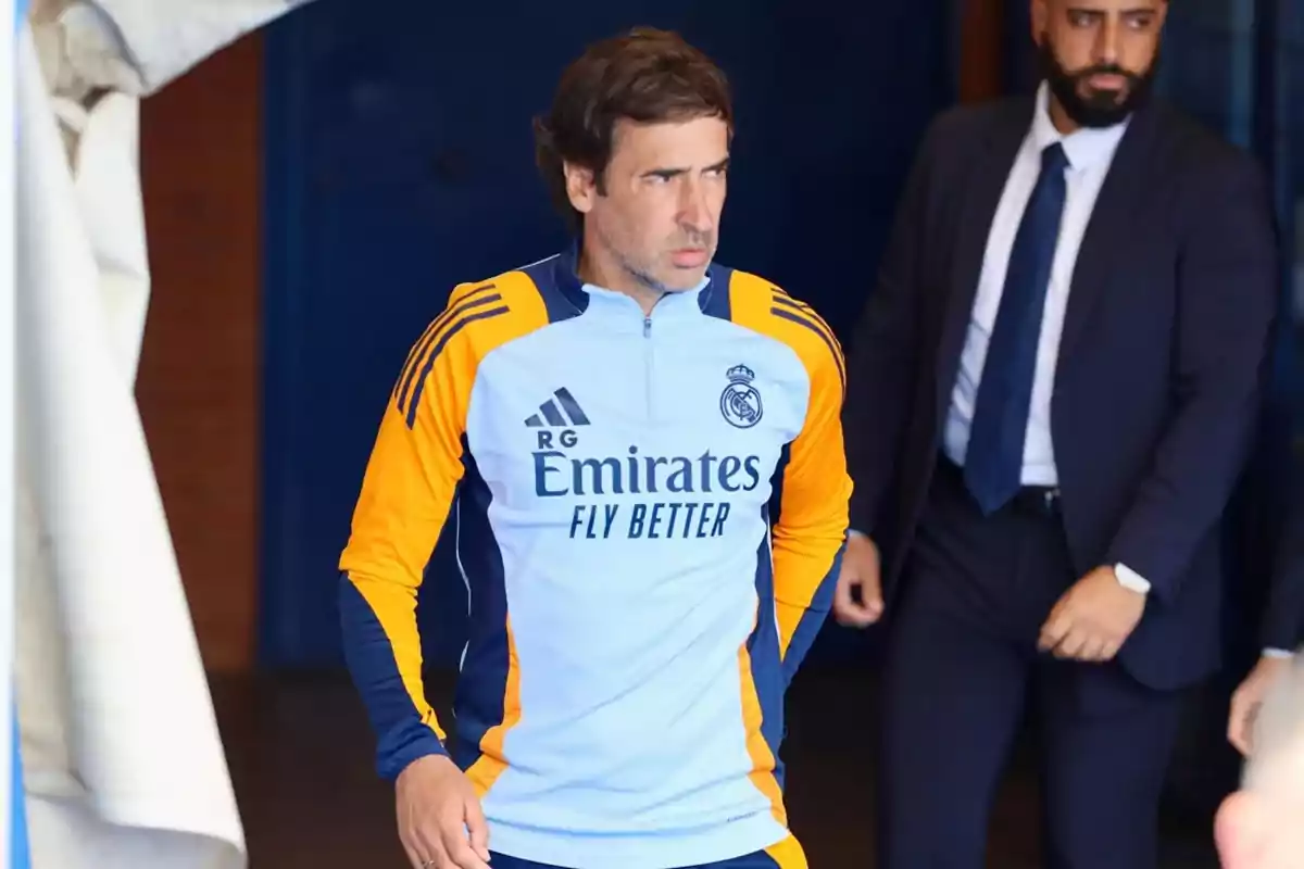 A man in Real Madrid sportswear comes out of a tunnel accompanied by another person in a suit. A man in Real Madrid sportswear comes out of a tunnel accompanied by another person in a suit.