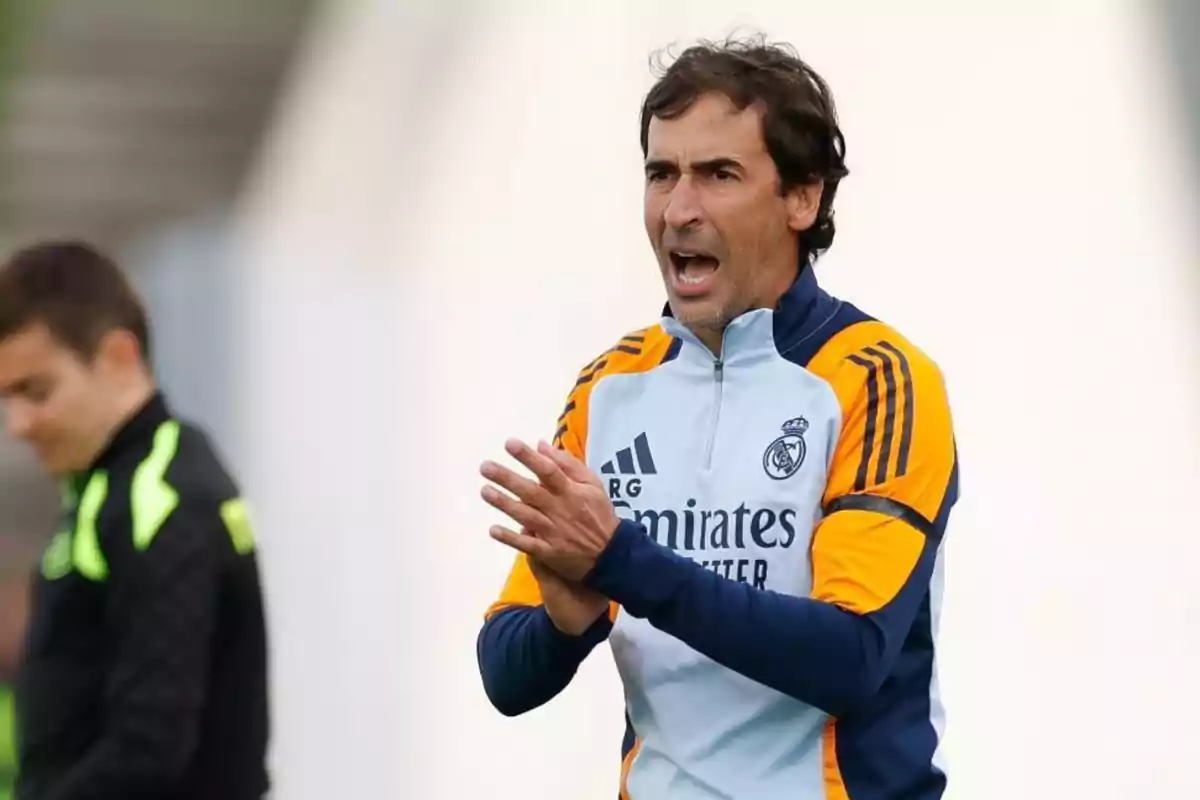 Entrenador de fútbol con chaqueta del Real Madrid dando indicaciones en un campo de entrenamiento Entrenador de fútbol con chaqueta del Real Madrid dando indicaciones en un campo de entrenamiento