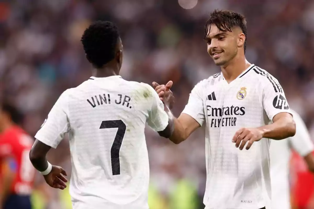 Dos jugadores de fútbol del Real Madrid celebran en el campo durante un partido. Dos jugadores de fútbol del Real Madrid celebran en el campo durante un partido.