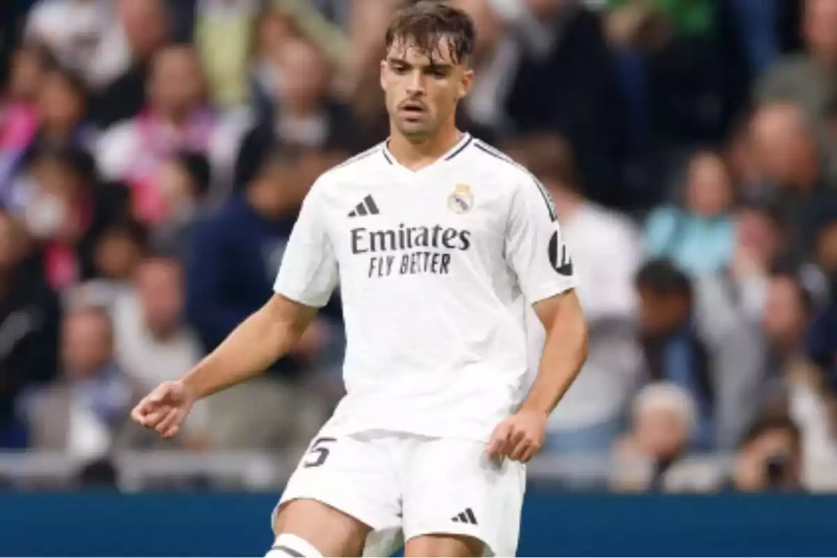 Jugador de fútbol con uniforme blanco del Real Madrid en el campo durante un partido. Jugador de fútbol con uniforme blanco del Real Madrid en el campo durante un partido.