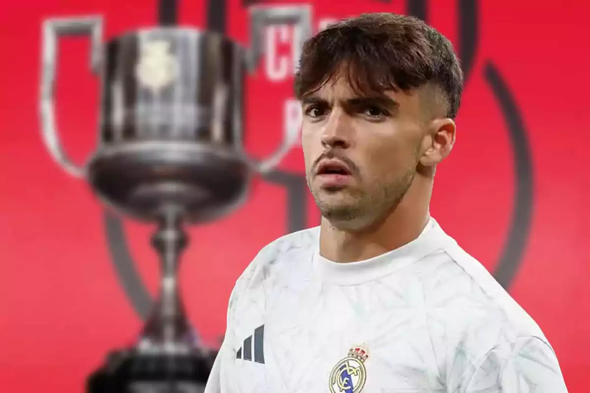 A soccer player in a white Real Madrid jersey appears in front of an out-of-focus trophy against a red background.