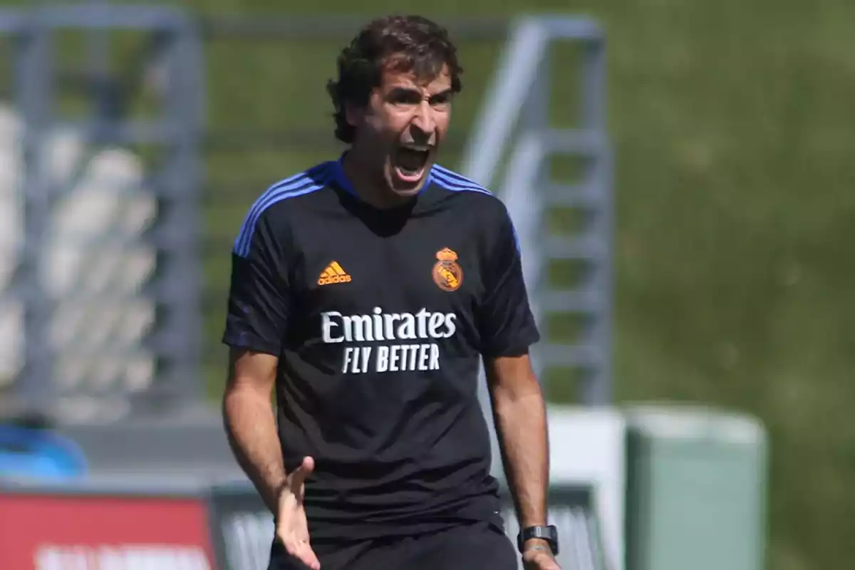 A man in a Real Madrid training uniform gestures intensely on a soccer field. A man in a Real Madrid training uniform gestures intensely on a soccer field.