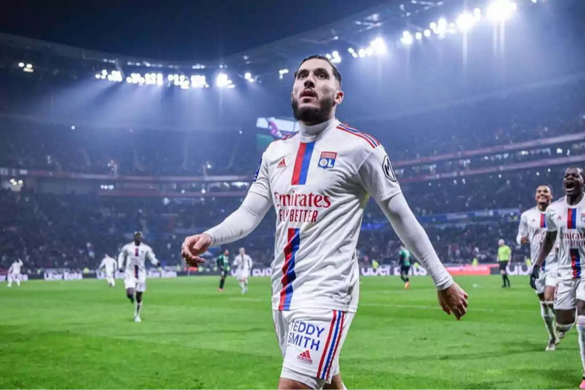 Soccer player in a white Lyon uniform walking in a lit stadium during a match. Soccer player in a white Lyon uniform walking in a lit stadium during a match.