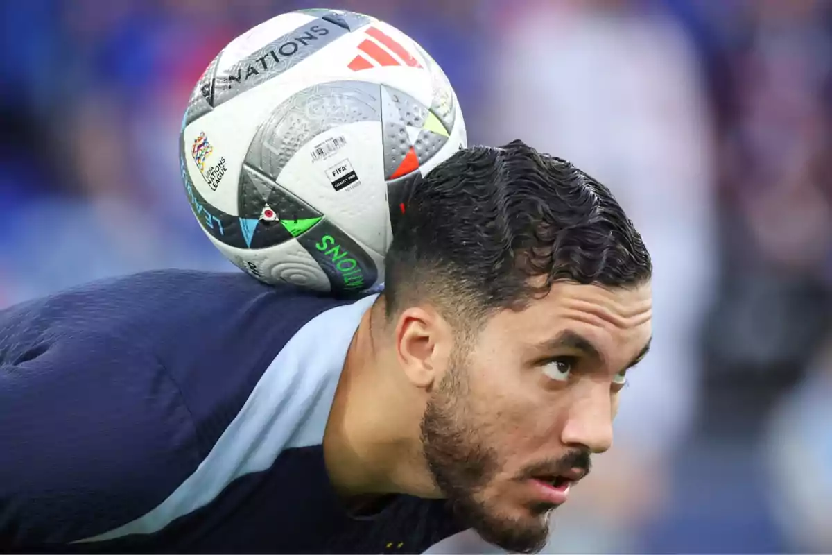 Futbolista sosteniendo un balón sobre su cuello durante un entrenamiento Futbolista sosteniendo un balón sobre su cuello durante un entrenamiento