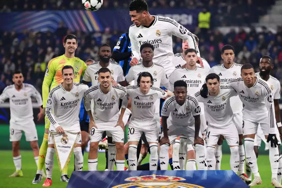 A soccer team posing on the field in their white uniforms.