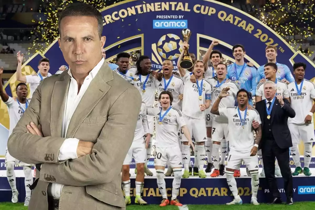 Un hombre de traje claro con los brazos cruzados frente a un equipo de fútbol celebrando con un trofeo en un estadio.