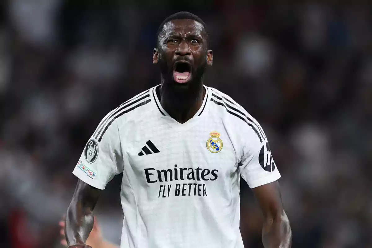 Jugador de fútbol con uniforme blanco del Real Madrid celebrando en el campo.