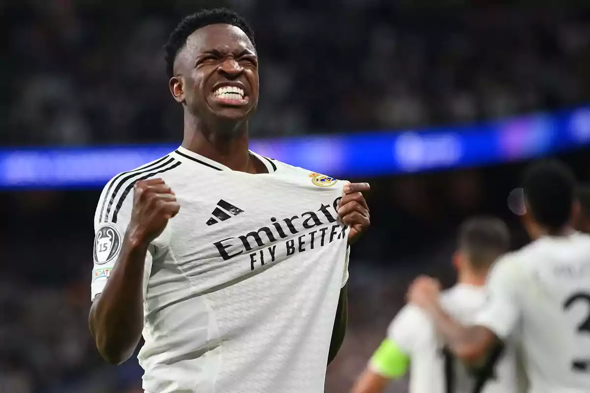 Un jugador de fútbol celebrando con emoción mientras sostiene la camiseta de su equipo.