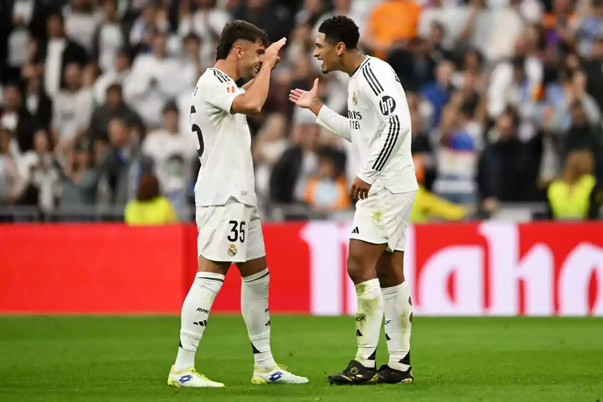 Two Real Madrid soccer players celebrate on the pitch during a game.