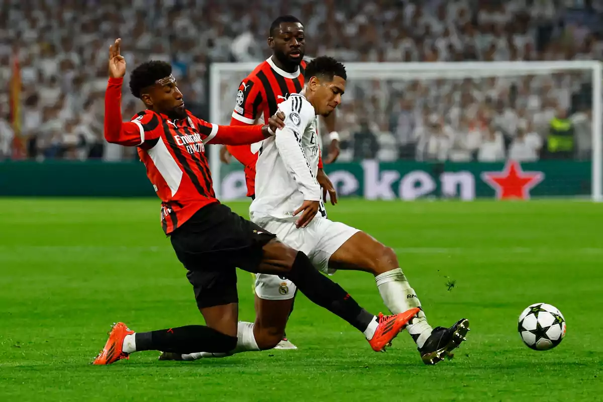 Two soccer players compete for the ball in a game while a third player watches in the background. Two soccer players compete for the ball in a game while a third player watches in the background.