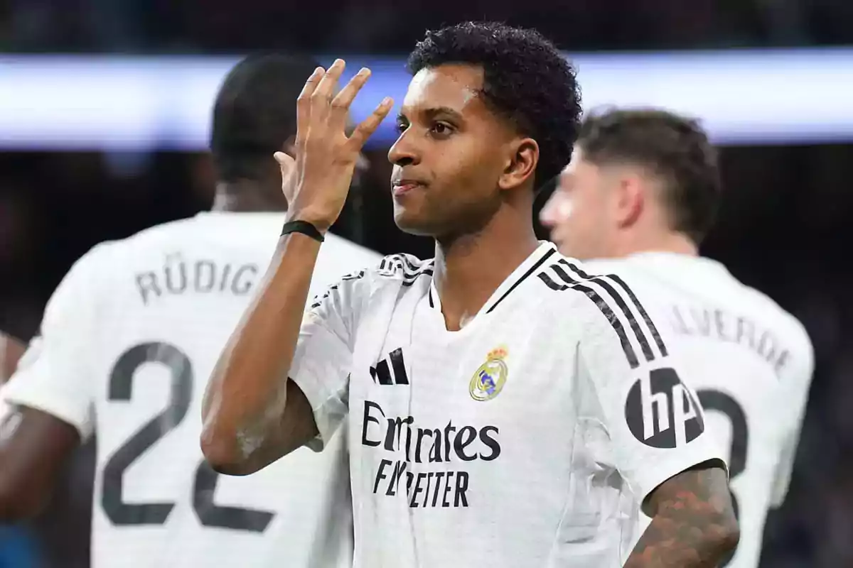 Un jugador de fútbol del Real Madrid celebra en el campo con compañeros al fondo. Un jugador de fútbol del Real Madrid celebra en el campo con compañeros al fondo.