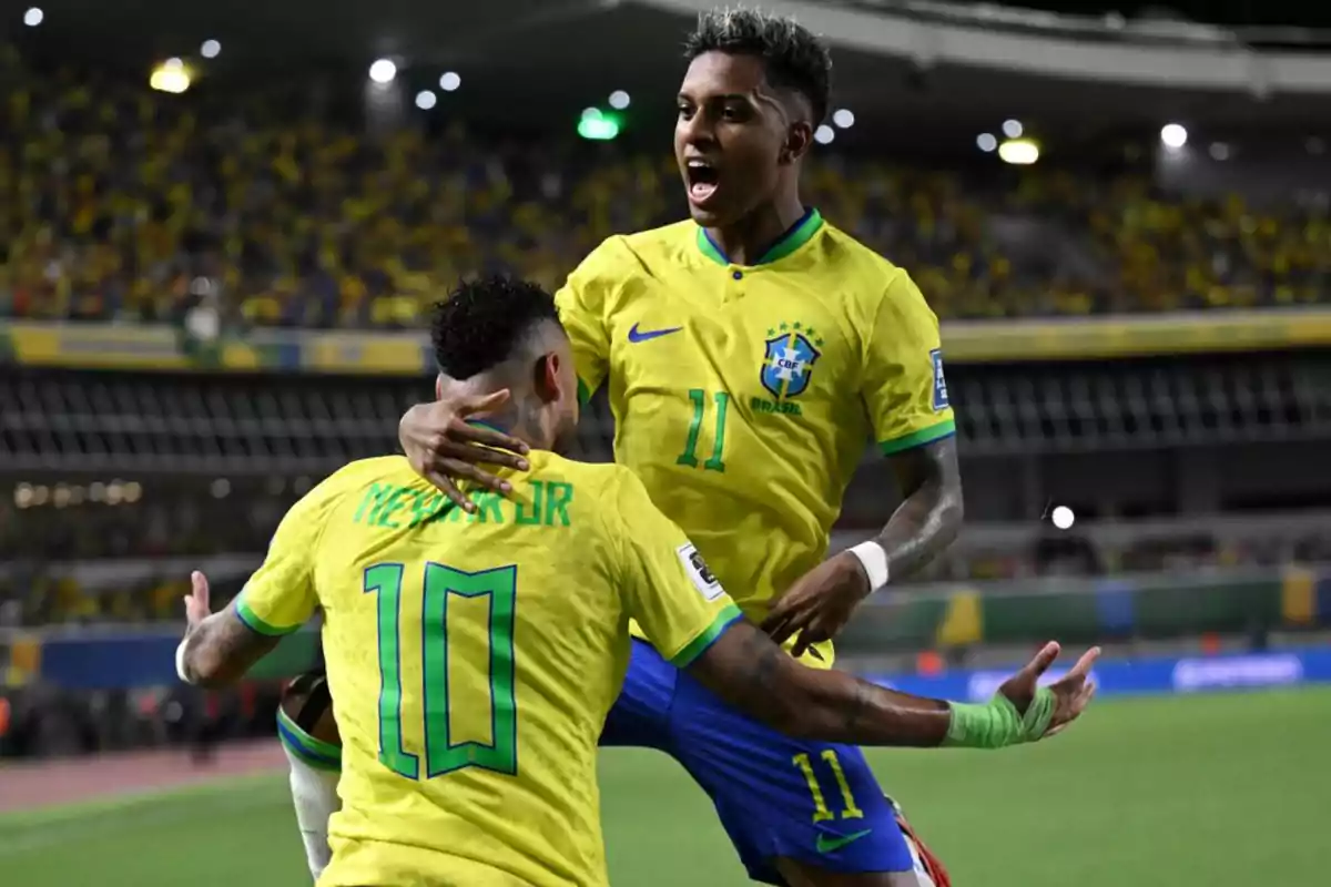 Two players from the Brazil national team celebrate a goal in a stadium full of fans. Two players from the Brazil national team celebrate a goal in a stadium full of fans.