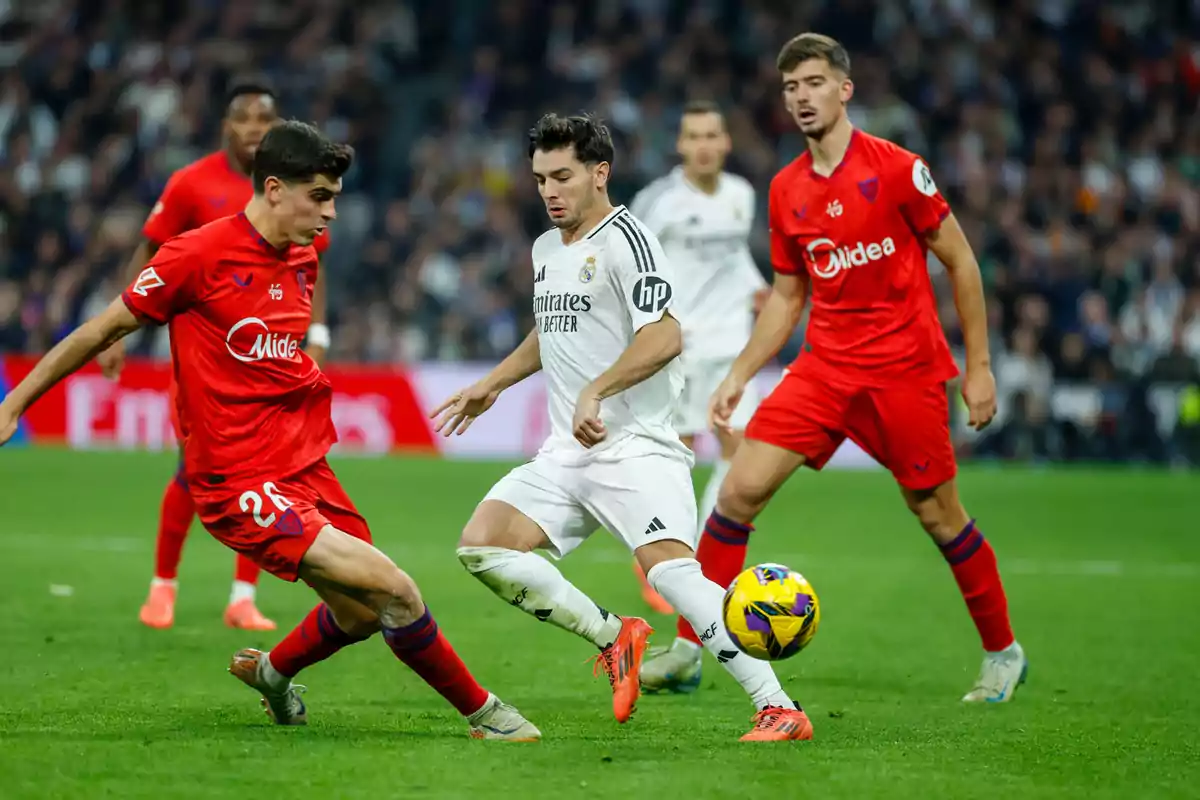 Jugadores de fútbol de dos equipos compiten por el balón en un partido.