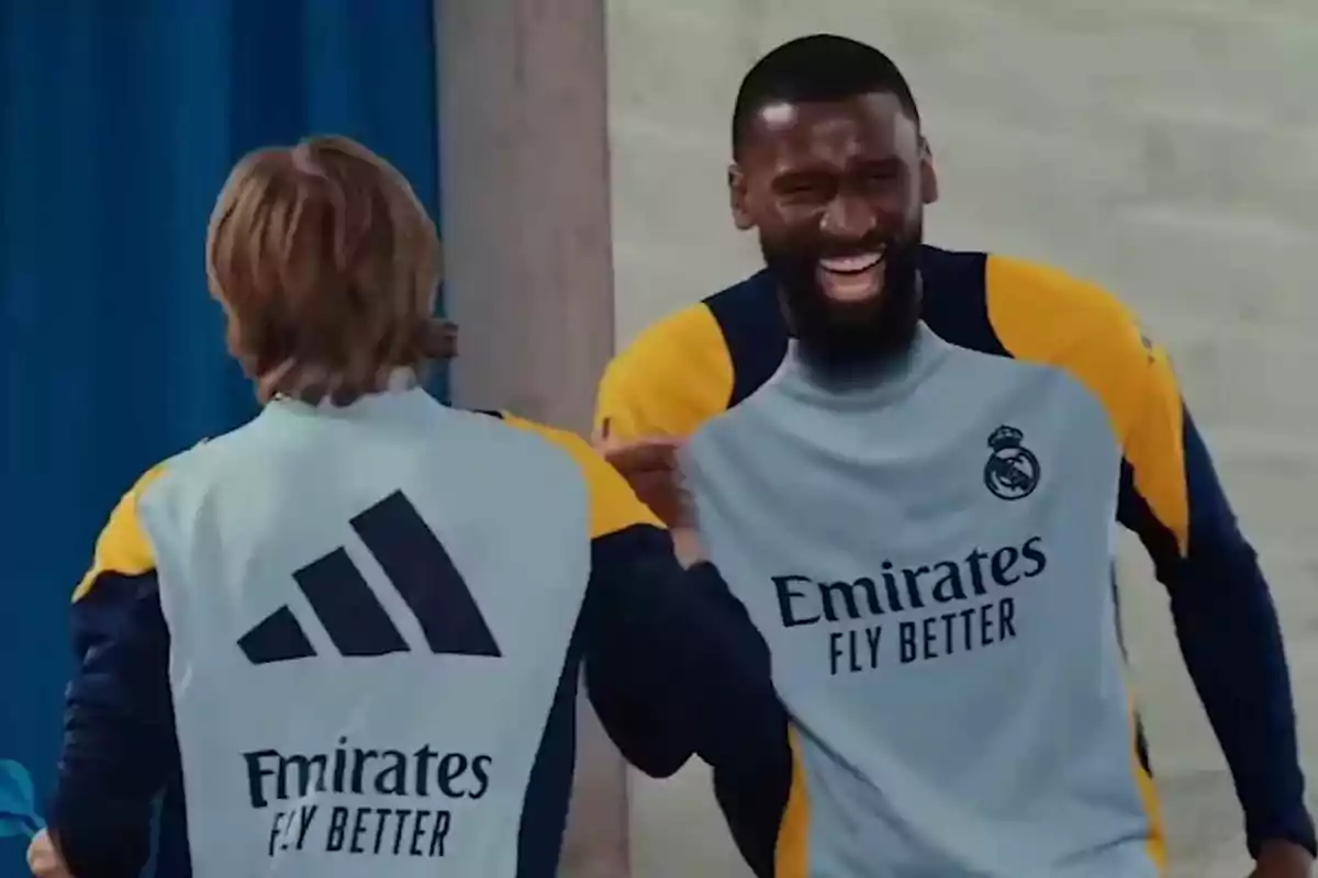 Two Real Madrid players smile and have fun during a training session, wearing the team's sportswear. Two Real Madrid players smile and have fun during a training session, wearing the team's sportswear.