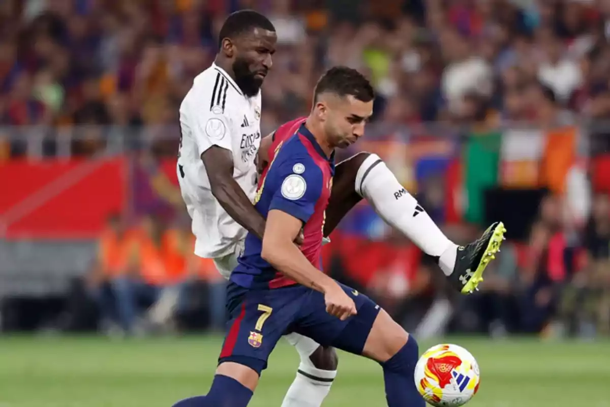 Two players compete for the ball in a match, one in a white uniform and the other in a blue and red uniform. Two players compete for the ball in a match, one in a white uniform and the other in a blue and red uniform.