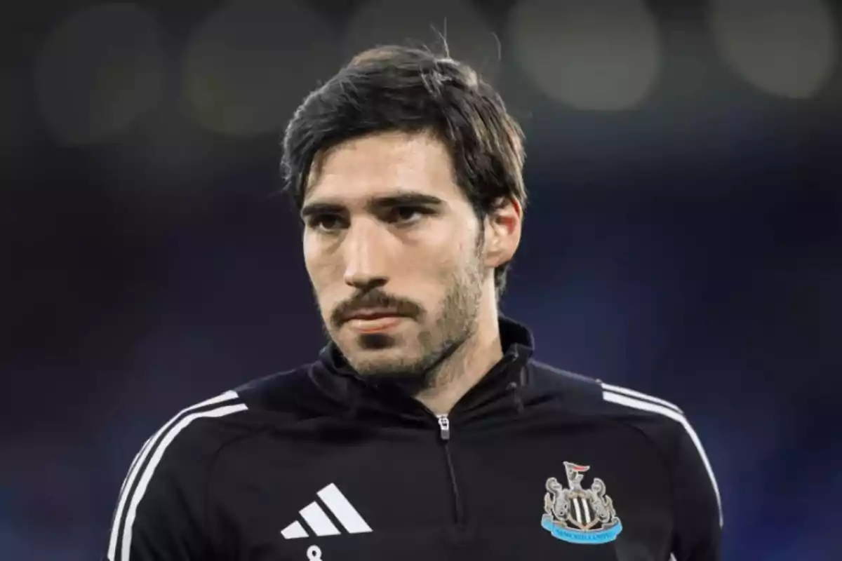 A man in a black sports uniform with a soccer team logo on the chest. A man in a black sports uniform with a soccer team logo on the chest.