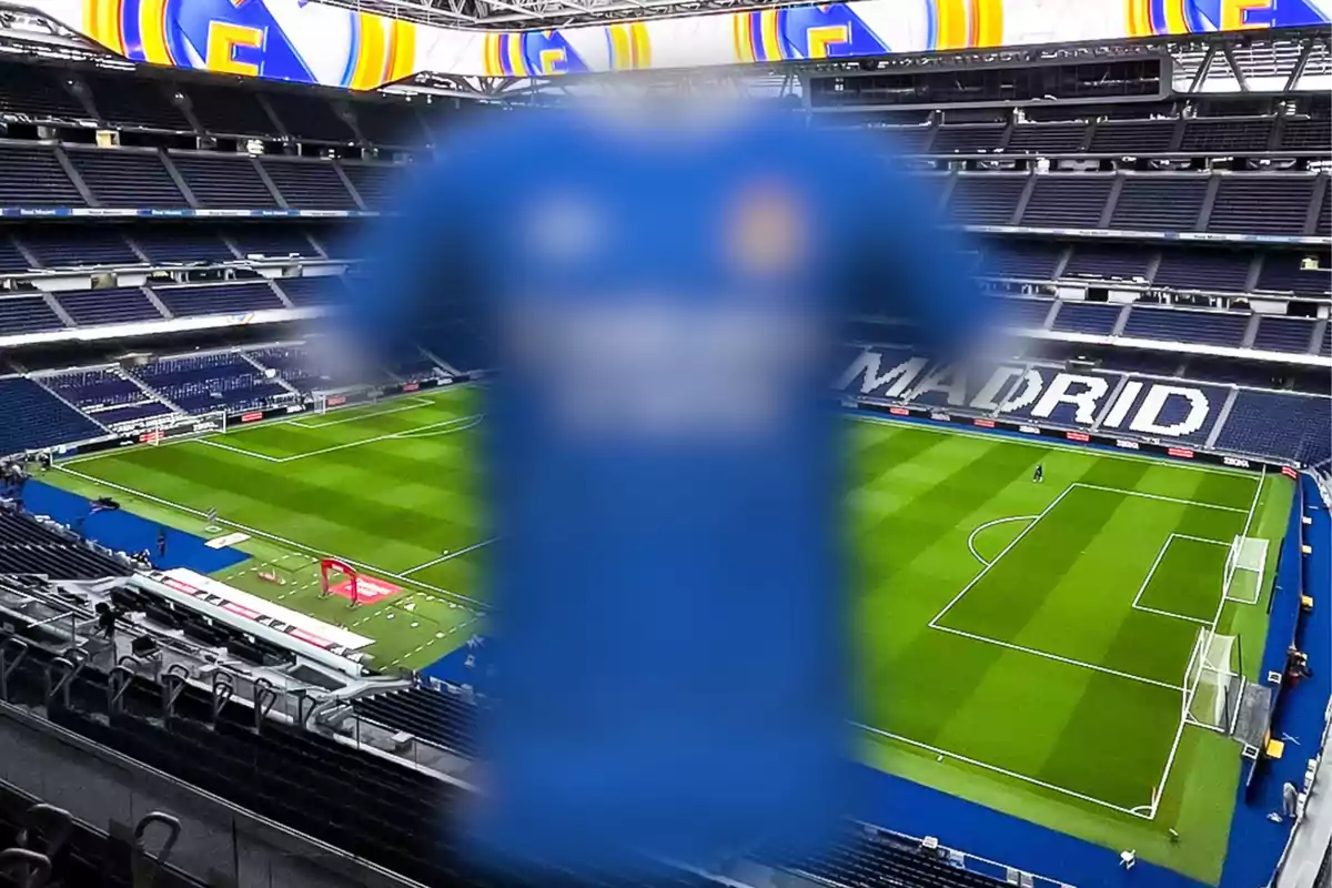 A blue jersey out of focus in the foreground with an empty soccer stadium in the background.