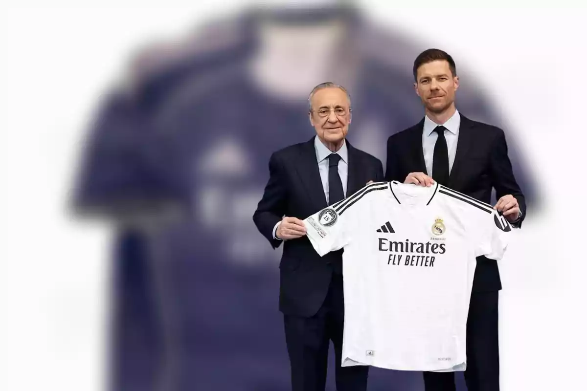 Dos hombres con traje sostienen una camiseta blanca del Real Madrid frente a un fondo desenfocado.