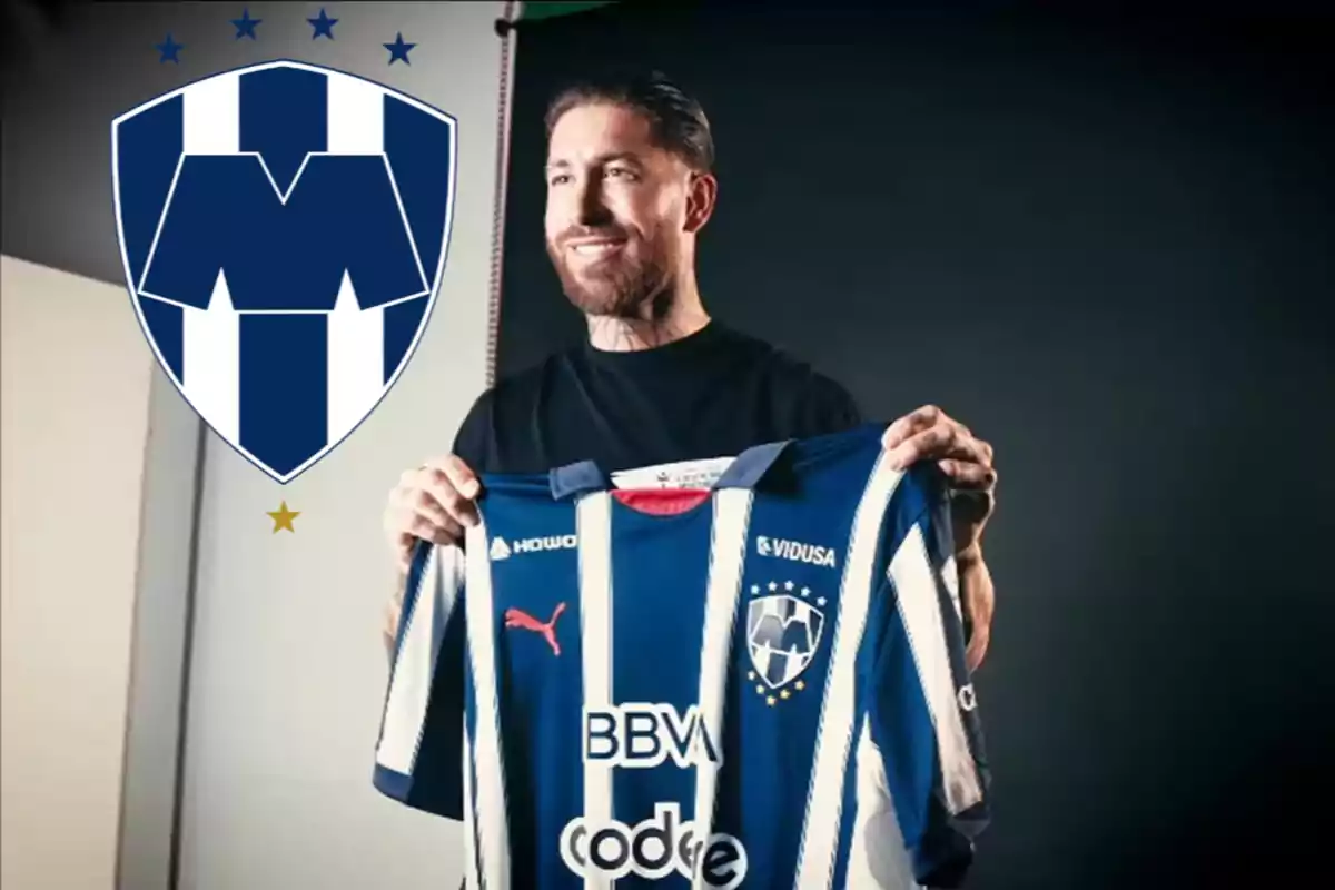 Un hombre sosteniendo una camiseta de fútbol del equipo Monterrey con el escudo del club a la izquierda.